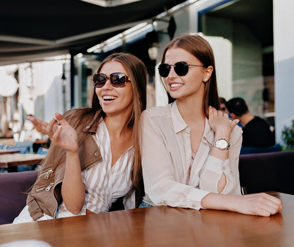 Подружки у кафе, на них одягнуті сонцезахисні окуляри жіночі Полароїд